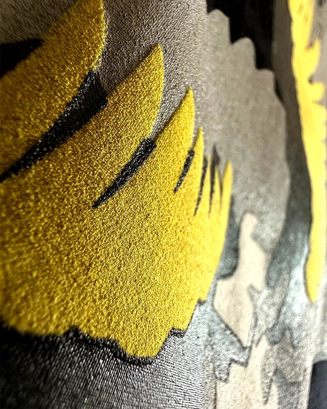 Close-up of a yellow and black leaf-shaped object on a textured surface