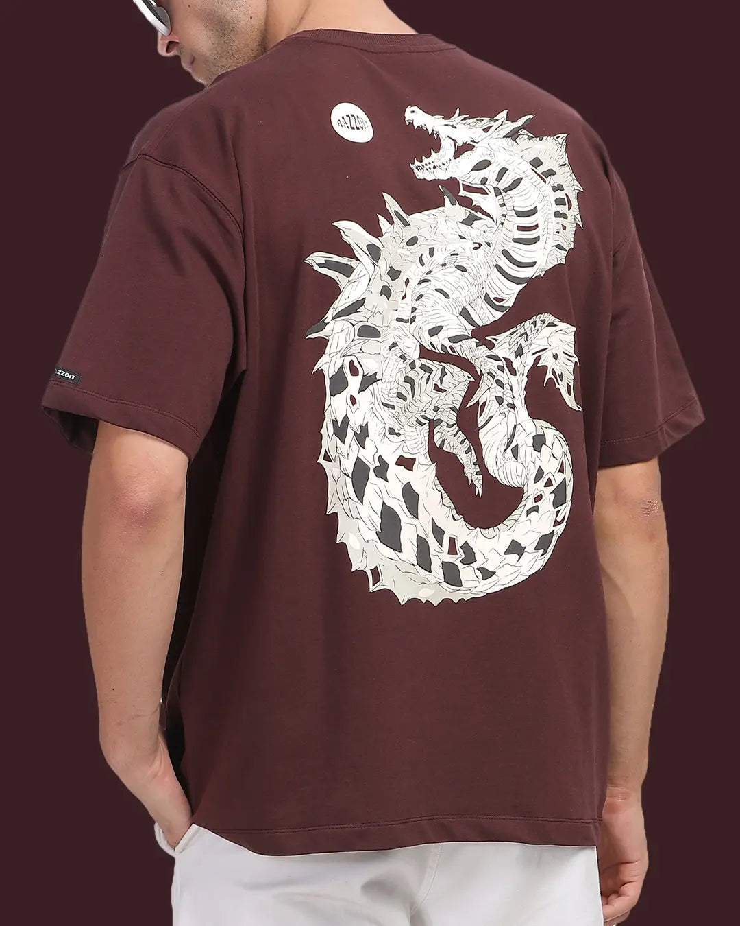 Person wearing a brown t-shirt with a white dragon design on the back against a dark background