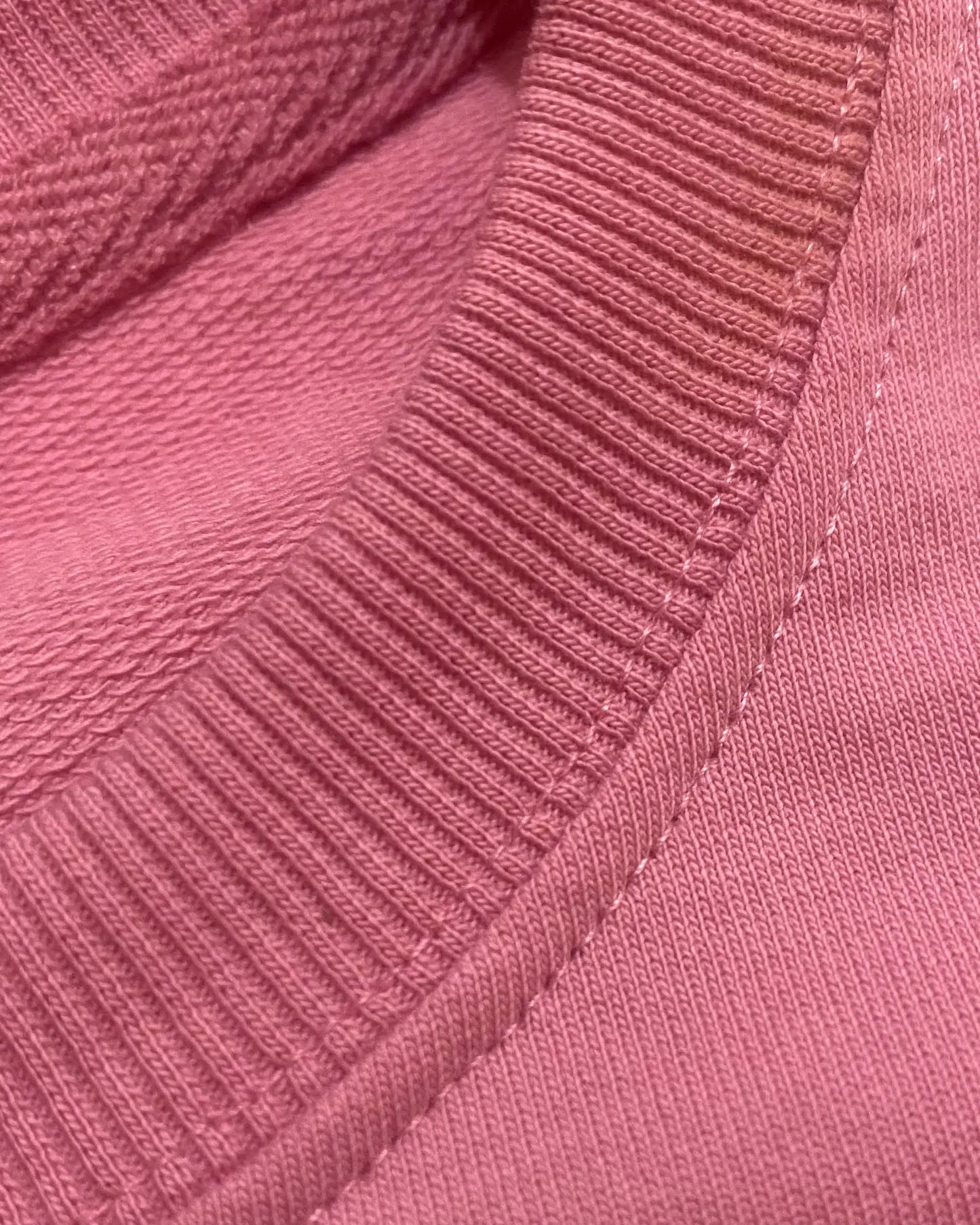 Close-up of a pink textured fabric with a focus on the stitching detail.