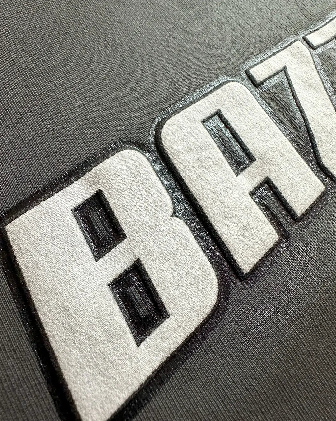Close-up of a textured 'BAA' logo on a gray background